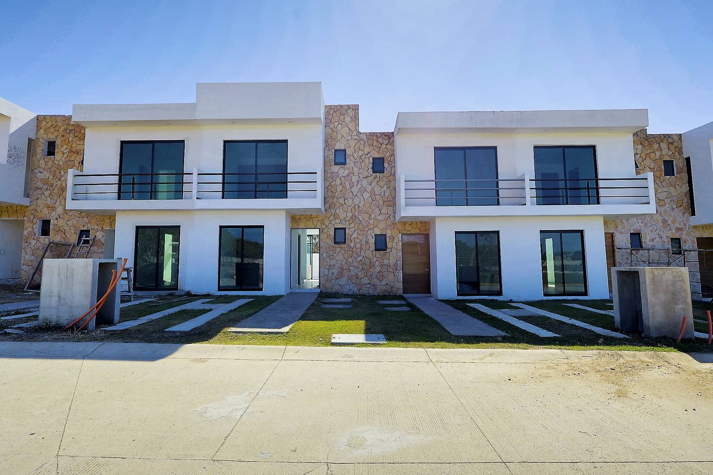 Fila de casas terminadas con fachada de piedra en Del Lago Residencial