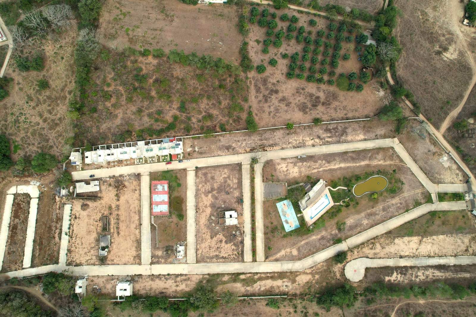 Vista aérea cenital de Del Lago Residencial con calles, casa club, lago y canchas